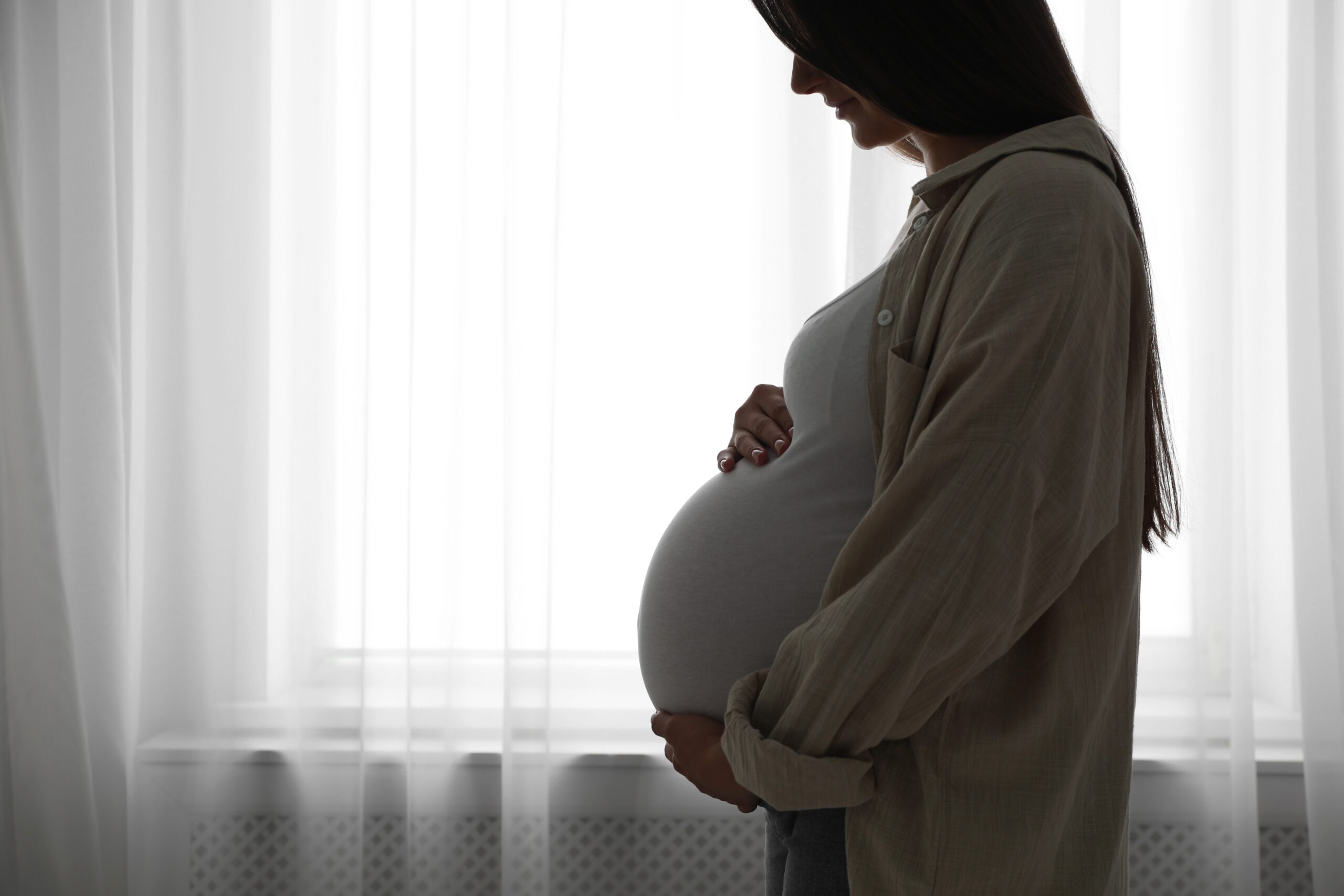 Pregnant woman gently holding her belly, representing the importance of PMU safety during pregnancy